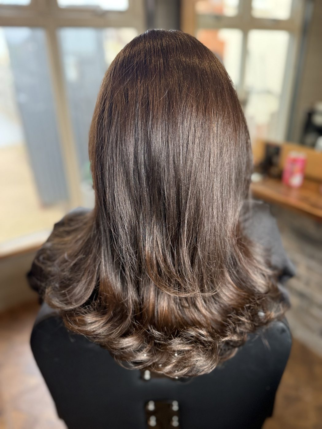 After: long brunette hair refreshed to a rich, glossy brunette with a bouncy blow-dry
