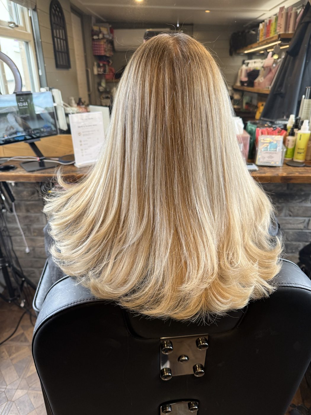 After: brassy lengths toned to a bright, creamy blonde with a smooth blow-dry